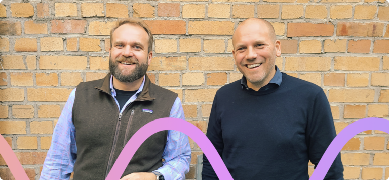 Chris Meidinger, Director of Sales Engineering, and Sven Grube, Director of International Expansion, stand in front of a red brick wall outside of Parloa's Berlin office